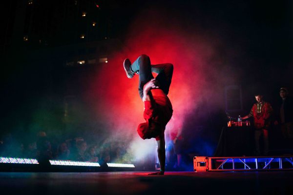 Homme sur scene faisant du breakdanse. Il est a l